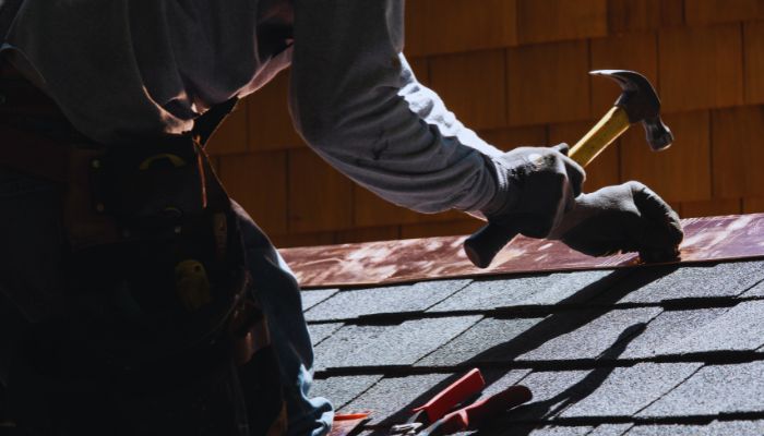 man nailing the roof with hammer 