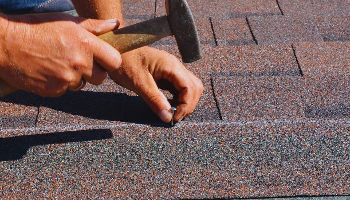 man nailing the roof with hammer