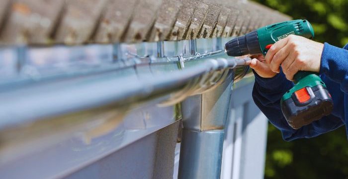 Worker trying to repairs the gutter with driller gun