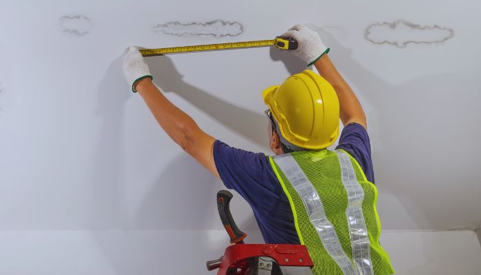 worker measuring the damage on the roof 