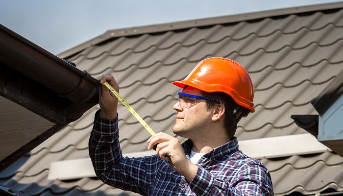 roof worker wearing orange hat and measuring the roof 