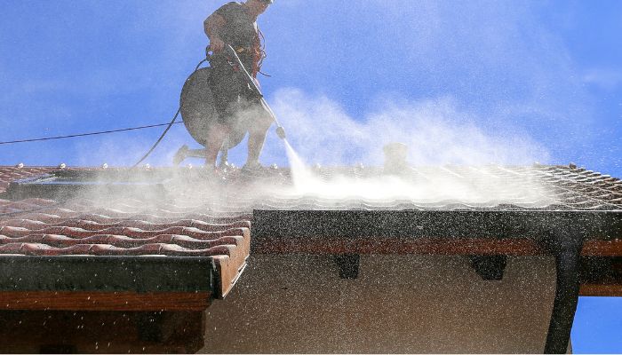 Man using pressure gun on roof top cleaning