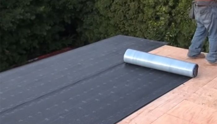 Man standing on roof with roof protect sheet 