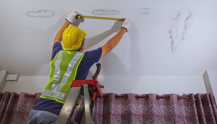 man measuring roof leak 