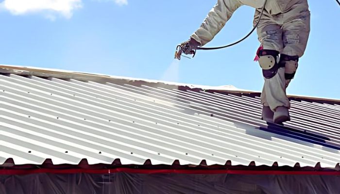 Man coating the metal roof with spray